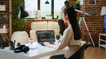Asian freelancer woman works on programming code in a modern office at home, using her laptop for computer science. IT specialist supports coding, web development and digital innovation. Camera A. photo