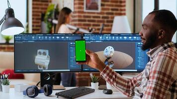 African american industrial designer works on 3D renders and isolated mockup, using digital tools and dual monitors. Engineer driven by creativity and technical expertise in design. Camera B. photo