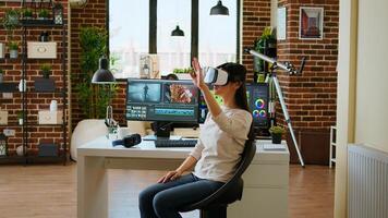 Asian modern editor using virtual reality glasses and mixing clips, using interactive gadget vr headset to edit and do color grading for a montage. editing software. Camera A. photo