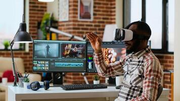 African american editor uses virtual reality glasses to do color grading, working with high tech vr headset and dual monitors at his home office. Filmmaker editing clips. Camera B. photo