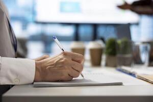 Financial consultant takes notes during a project briefing meeting, working on allocating available resources to meet the business objectives. Expert making future projections. Close up. photo