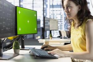 Woman testing and deploying machine learning programs and systems on isolated screen PC, solving tasks. Software engineer checking code on chroma key PC, sitting at desk in office photo