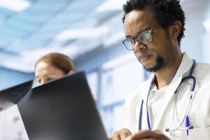 Diverse team of medics examining x ray results and healthcare data in a cabinet meeting, consulting the colleagues before putting a diagnostic. Physicians working together for healthcare recovery. photo