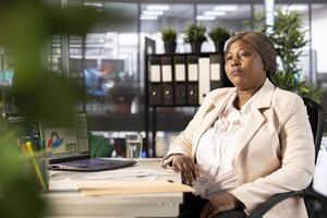 Businesswoman in office at computer desk developing and implementing business strategies to improve operational efficiency and profitability. African american manager with executive role in company photo