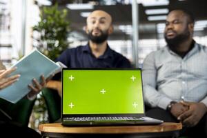 Colleagues preparing for business meeting to plan project, using green screen laptop to design marketing strategy. People doing research analysis for startup organization using mockup notebook photo