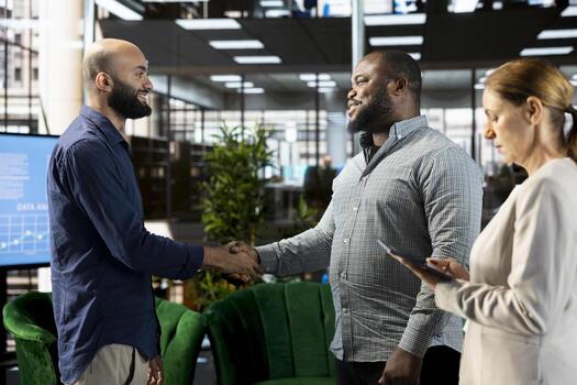 Joyful manager doing handshake with shareholder in office, coordinating company administrative operation. Cheerful supervisor shaking hands with business partner, talking about performance metrics photo