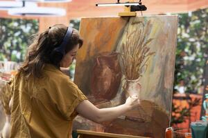 In a peaceful studio, female painter uses oil paints to create a masterpiece on canvas. Showing her skill and inspiration to create a nature inspired paintwork, creative work in atelier. photo