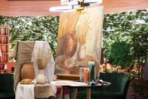 Empty art and craft workshop with a rustic beautiful painting on canvas, creative work with watercolor paint in a modern contemporary atelier. Artistic masterpiece with paint tubes and tools. photo