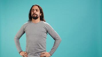 Portrait of man standing confidently with hands on hips, posing against plain studio background, projecting confidence and strength. Person holding assertive stance posture, camera B photo
