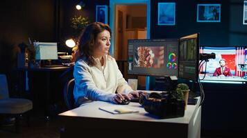 editor selecting key frames to use while doing montage, working from home on computer. Cheerful woman using mouse to edit movie project footage in office, camera B photo