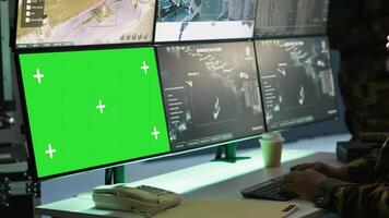 Air force officer performing tactical level surveillance in command room using mockup screen. Military specialist using radar on chroma key gear to look at assault zones, camera A photo