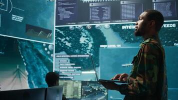 Team of military specialists operate in a secret service command post, managing surveillance systems and data protection to ensure the safety and security of classified information. Camera B. photo