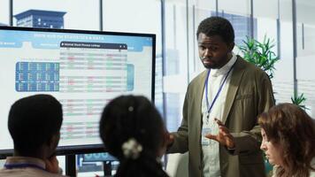 Business professional staff gather to review project development progress, detailed reports and statistics on interactive board to ensure strategic objectives. Diverse work team in meeting. Camera A. photo