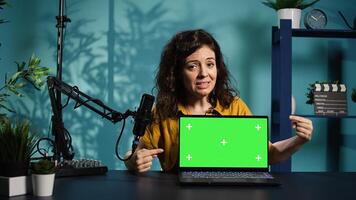 Woman in home studio using recording tech to capture live broadcast, reviewing mockup laptop. Internet show host filming electronics haul, presenting isolated screen notebook for viewers, camera B photo
