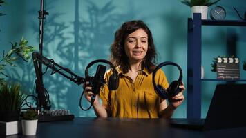 Audio technician presenting professional headphones in different price ranges to audience, comparing them to find winner. Expert recommending listening devices to fans, doing review, camera B photo