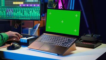 Music producer mixing and mastering songs on digital post production pc interface, green screen display. Artist adding sound effects and adjusting volume levels to produce new music. Camera A. photo