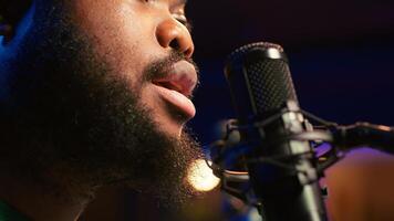 Artist records his voice on microphone in home studio singing a song composed by him. Skilled musician using recordings and lyrics to edit in post production, mixing and mastering session. Camera A. photo
