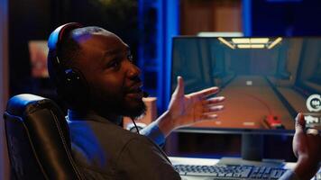 Pro gamer wearing headphones playing game, teaching audience esports needed skills. Content creator in gaming chair talking with audience, filming tutorial on how to defeat enemies, camera A photo