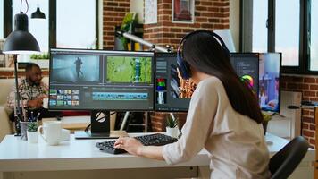 Asian filmmaker woman putting headphones on and working on production at a home office, mixing clips. Office setup with a software perfect for color grading in post production. Camera A. photo