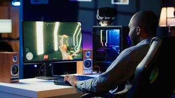 Man having fun by playing videogames on gaming PC at computer desk, enjoying day off from work. Gamer battling enemies in online multiplayer shooter from the comfort of his home, camera A photo
