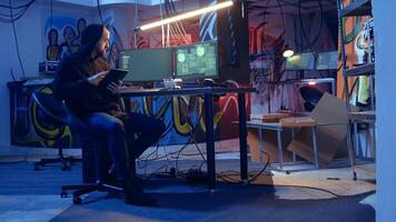 Man arriving in underground bunker, using it to mask his location while committing international espionage. Spy using tablet and computer systems to steal governmental secrets photo