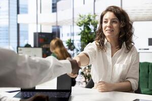 HR department worker doing handshake with hired man after implementing diversity recruitment strategy for company. Headhunter reaching agreement with african american person, shaking hands photo