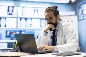 General practitioner working with hospital records and test results to find the diagnosis in his cabinet, examining x rays and reports. Doctor doing research for disease prevention and treatment. photo