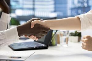 Startup manager shaking hands with newly hired worker, welcoming her doing onboarding process. Businesspeople meeting for consultation, doing polite greeting handshake, starting collaboration photo