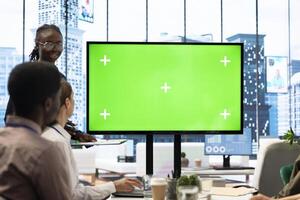 Team members from a business corporation use isolated mockup screen, discussing details and progress for a new project during corporate meeting. Employees informed about marketing developments. photo