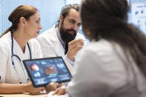 Group of diverse doctors in a treatment center reviewing brain scan results, examining neurology mri tests. Experts collaborate on diagnostics, treatment plans and disease prevention. Tomography photo