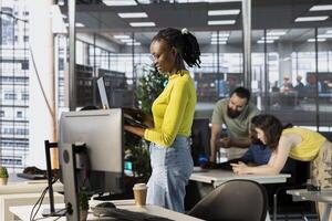 Company personnel sitting at desks in office, imputing data on computers. Woman typing on laptop keyboard next to staff members in modern relaxed workplace solving tasks during job shift photo