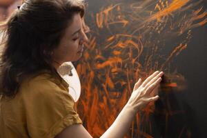 In an art studio, painter uses watercolor paint to create a finger painted masterpiece. Creative talented artist showing her inspiration to create a rustic colorful artwork with handprints. photo