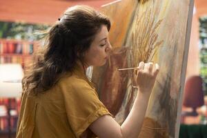 Inspired artist works on a canvas to create a masterpiece in atelier, using bristles to apply dye with precision. Showing her skill during creative process to create unique painting for the gallery. photo