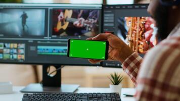 Freelancer male editor works from home with green screen, using dual monitors and tech tools for color grading on a project. Modern remote work and productivity. Camera B photo