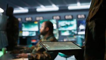 Army operative using tablet in command center housing operational missile defense system designed to intercept ballistic rockets. Close up of expert using tracking software on device, camera B photo