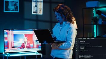 Woman walking in apartment designing and developing software applications using laptop. IT professional standing in living room, implementing and maintaining company systems, camera A photo