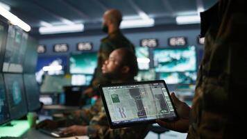 Army professional employing AI tech to improve military combat systems and missiles monitoring. African american IT admin uses neural networks to enhance combat operational capabilities, camera B photo