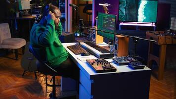Artist composer recording a new track on his home studio microphone, editing his song with professional gear. Adjusting volume levels and adding sound effects, mix and master. Camera B. photo
