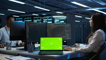 Programmers in data center manage and maintain databases using chroma key notebook, ensuring data integrity and security. Experts updating server room systems using isolated screen laptop, camera B photo