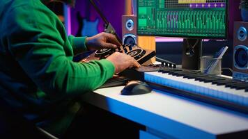 Skilled music producer composing new soundtracks on console and daw software, working with stereo gear in home studio. Young artist engineer uses pre amp knobs, signal processing. Camera A. photo