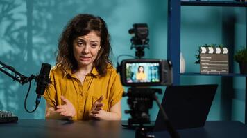 Enthusiastic internet show host hitting the record button on professional camera, using microphone to talk about today topic with subscribers. Media star filming creative vlog, camera A photo