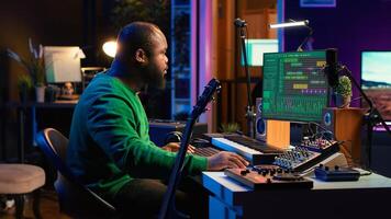 Musical producer prepares to record tunes on acoustic instrument, working in personal home studio to record soundtrack. Sound composer recording guitar music, editing with mixing console. Camera A. photo