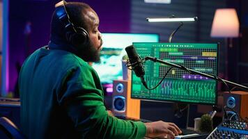 Young artist playing piano keys and singing song on microphone, composing his new music and mixing the tracks on digital interface. Producer technician composing melody with gear. Camera A. photo