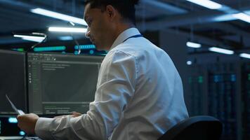 Admin in data center maintaining accurate documentation of infrastructure, configurations and procedures, generating reports. Server room employee doing workspace disaster recovery planning, camera A photo