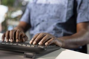 Worker inputting revenue figures on desktop PC in office. African american man at desk focused on typing company statistical numbers, working hard to finish job before deadline photo