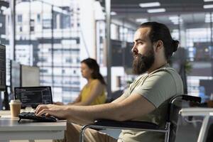 Admin with disability in inclusive workspace utilizing cloud computing resources and platforms to train machine learning models. Person with paraplegia monitoring and maintaining company systems photo
