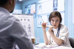 General practitioner consults patient about diagnostic test results, utilizing medical technology for accurate analysis and patient care management in a clinical environment. Healthcare provider. photo
