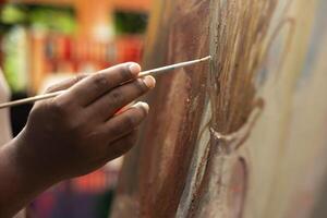 African american artist applying acrylic dye with his paintbrush on canvas, showing his skill in creating a masterpiece for the art gallery. Working with professional supplies. Close up. photo