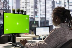Female executive seated at her workstation with isolated copy space multitasking, analyzing financial reports to support strategic business goals and decision making processes. photo