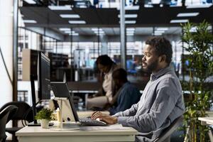 African american businessman reviews financial plans using online tools for problems solving and strategy planning. Expert managing enterprise objectives and business operations, focused on success. photo